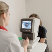 ophthalmologist checking eyesight of female on vision screener with eye illustration on display in clinic